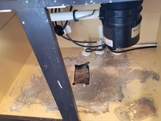 Sink cabinet base with an access hole cut under the plumbing so it can dry